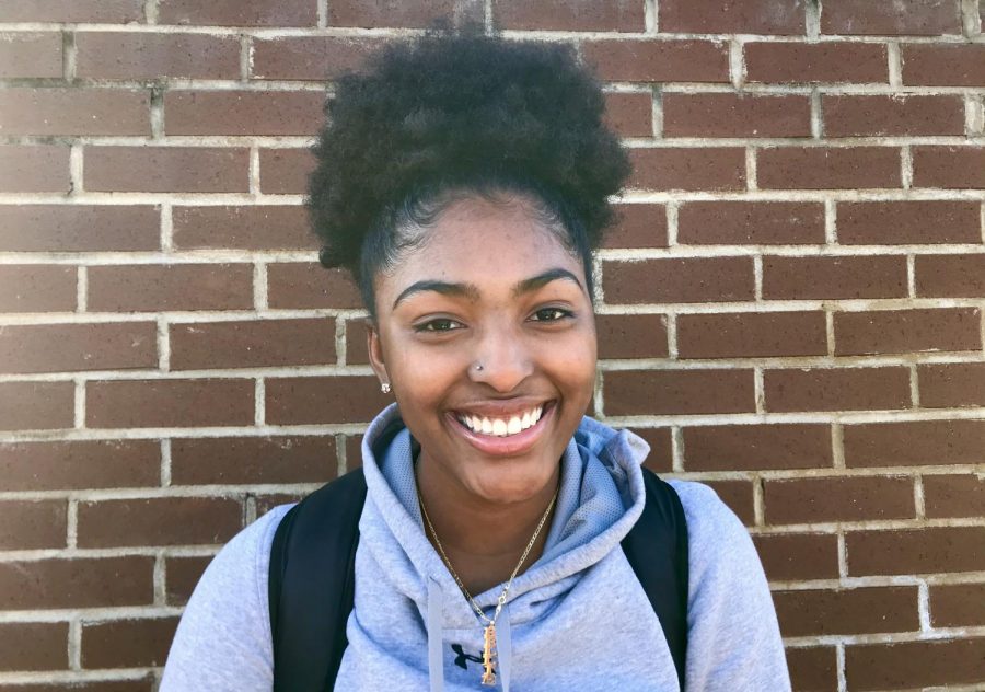 Senior Kellie Pearson stands proudly with her natural hair, and poses with a smile.