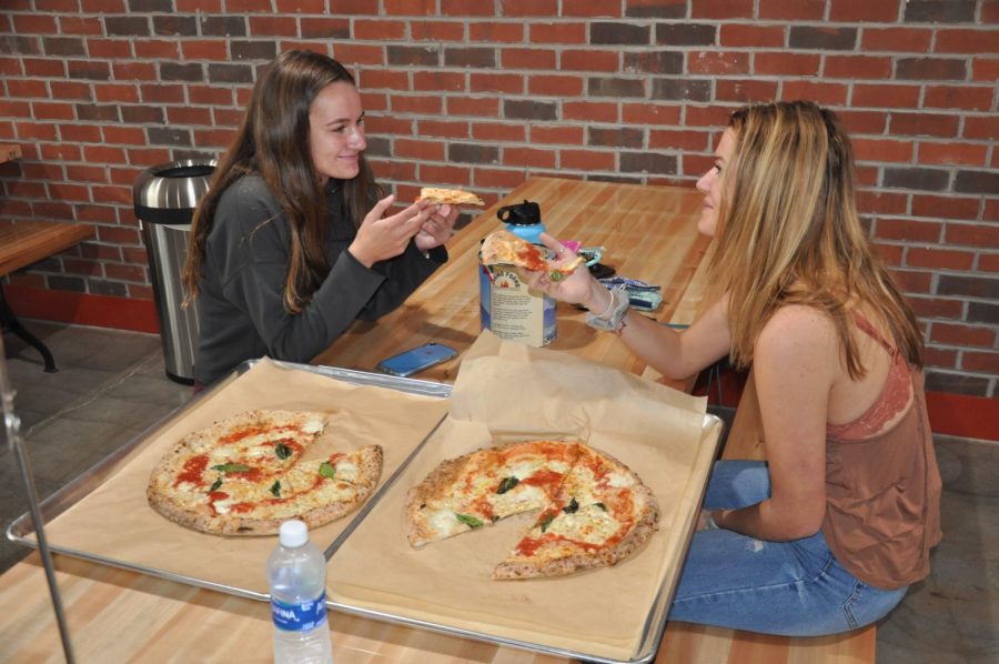 Seniors Caroline Adams (left) and Kellen Gentry (right) enjoy their first meal at the Cugino Forno in Clemmons. The restaurant was excited to finally open last week.
