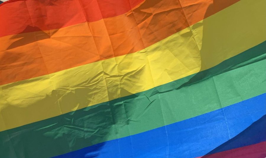 A photo of a rainbow pride flag, waving in the wind.