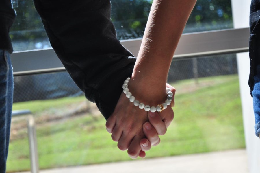 Two students hold hands in public. 