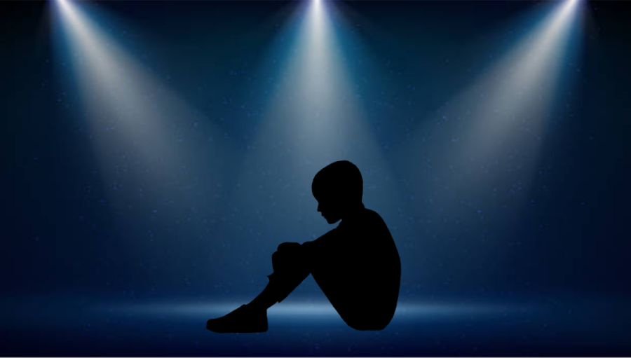 A child sits beneath an isolating spotlight.