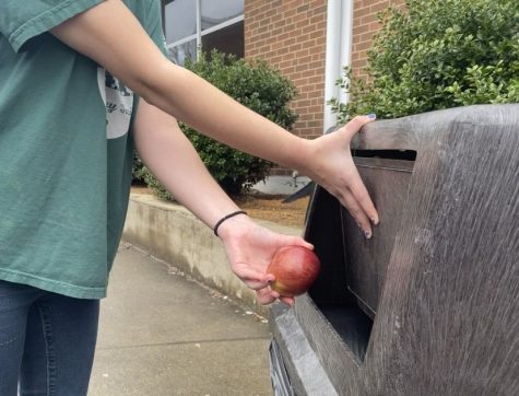Student throws away untouched piece of fruit.