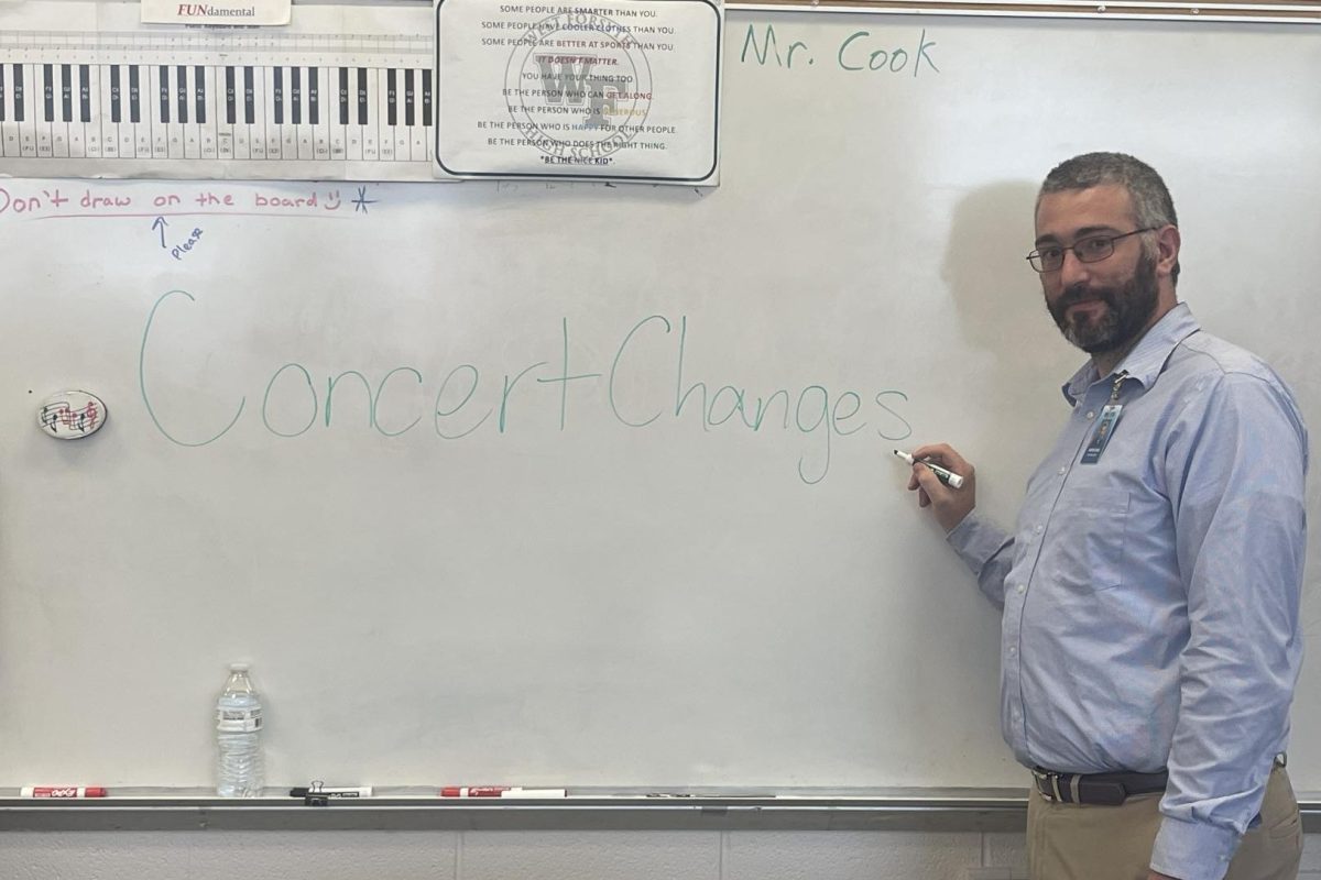 Mr. Cook the chorus teacher writing "concert changes" on a white board